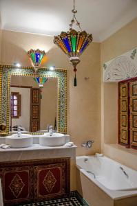 La salle de bains est pourvue de 2 lavabos, d'une baignoire et d'un miroir. dans l'établissement Riad Esmeralda, à Marrakech