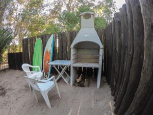 a outdoor grill with two chairs and a bench next to a fence at Cabaña de mar in Quequén