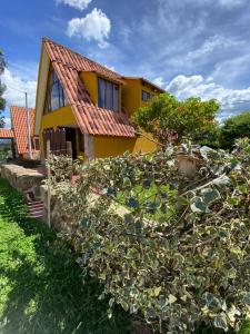 una casa amarilla con un seto de cactus delante de ella en Cabaña Villa Makus, en Paipa
