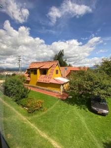 una casa amarilla con un coche aparcado delante de ella en Cabaña Villa Makus, en Paipa