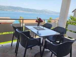 einen Tisch mit Stühlen und eine Vase mit Blumen auf dem Balkon in der Unterkunft Apartments Jelica in Trogir