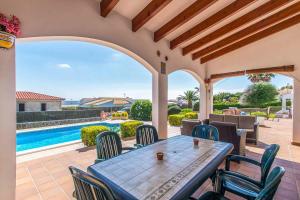 a patio with a table and chairs and a swimming pool at Villa Tuduri in Binibeca