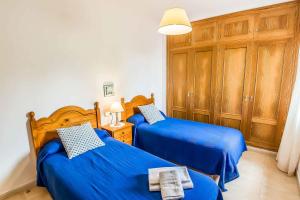 two blue beds in a room with wooden cabinets at Villa Tuduri in Binibeca