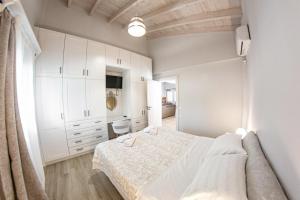 a white bedroom with a bed and white cabinets at Corfu Cicada House in Corfu Town