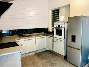 eine Küche mit weißen Schränken und einem Kühlschrank in der Unterkunft Appartement Cosy design in Schœlcher