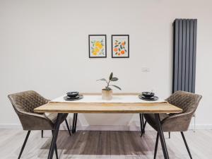 a dining room table with two chairs and a plant on it at Modern 2 bed flat near Wembley Stadium in London