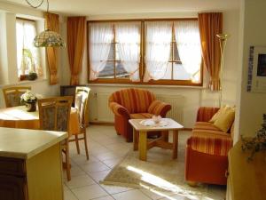 uma sala de estar com cadeiras, uma mesa e janelas em Lovingly furnished holiday apartment in our Black Forest house em Gutach