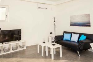 - un salon avec un canapé noir et une télévision dans l'établissement Villa Paradiso Ena, à Agia Pelagia
