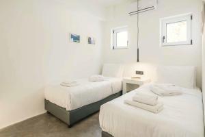 two beds in a room with white walls at Villa Paradiso Ena in Agia Pelagia +12 photos