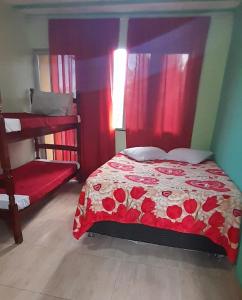 um quarto com uma cama com um edredão vermelho em Hospedagem Recanto do Lago em Angra dos Reis