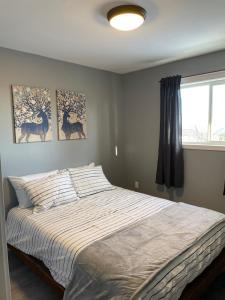 a bed in a bedroom with two paintings on the wall at Sunrise Mountain view Skidegate House 