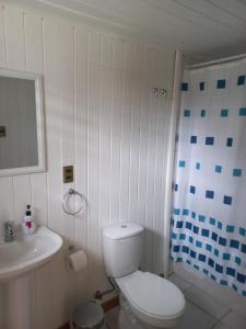 Baño blanco con aseo y lavamanos en Hostería Alemana en Villarrica