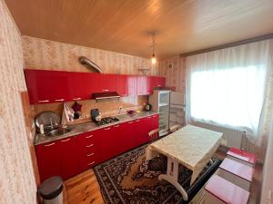 uma cozinha com armários vermelhos e uma mesa em Orchard em Quba