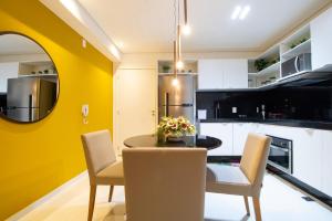 une cuisine avec une table et des chaises et un mur jaune dans l'établissement Apartamento com Varanda e Vista Temporada MME, à Maceió