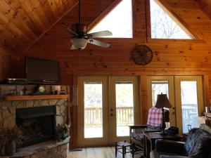 uma sala de estar com uma ventoinha de tecto e uma lareira em Glens of Antrim Mountain Cabin em Waynesville