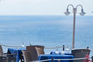 una mesa con mesas azules y sillas con el océano en el fondo en Hotel Sa Barrera - Adults Only, en Cala'n Porter