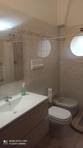 bagno con lavandino, servizi igienici e finestra di porta merlonia house trilocale a Forlì