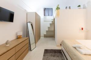 1 dormitorio con cama, espejo y TV en Cortile Bellini, en Catania