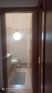 La salle de bains est pourvue de toilettes blanches et d'une lampe. dans l'établissement porta merlonia house trilocale, à Forlì