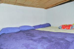 Cama en habitación con sábanas y almohadas moradas en MIRADOR DE MARCURA, en Paipa