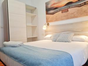 サン・セバスティアンにあるPension Yoldiのベッドルーム(白い大型ベッド1台、青いベンチ付)