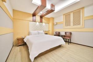 a bedroom with a large white bed and a desk at Cheonan Star Hotel in Cheonan