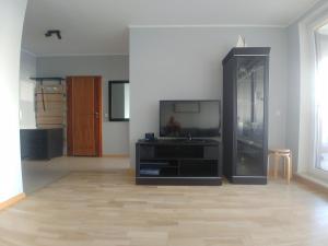 a living room with a tv and a wooden floor at Aquamarina Międzyzdroje in Międzyzdroje