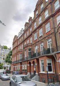 un gran edificio de ladrillo con coches estacionados frente a él en Luxury Apartment South Kensington en Londres