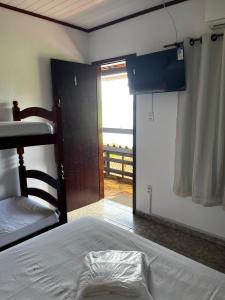 - une chambre avec un lit et une porte donnant sur un balcon dans l'établissement Luar de Araçatiba Suítes, à Praia de Araçatiba