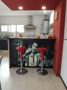een keuken met twee rode krukken voor een aanrecht bij La Casa de Vero en Acantilados in Mar del Plata