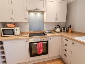 a kitchen with white cabinets and a stove top oven at Tawny Cottage in Scarborough