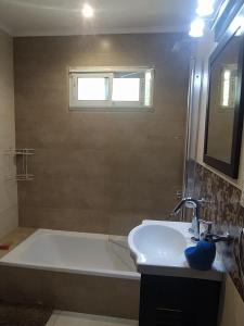 een badkamer met een wit bad en een wastafel bij La Casa de Vero en Acantilados in Mar del Plata
