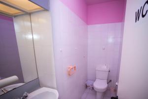 a pink bathroom with a toilet and a sink at private room in a shared flat at best location in Limassol