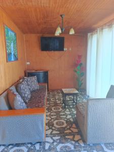 sala de estar con sofá y TV en cabañas Te Pito Kura, en Hanga Roa
