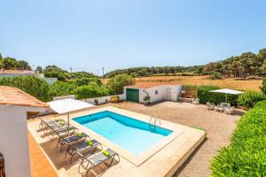 a swimming pool in a yard with chairs and a house at Villa Xaloc in Port d'Addaia