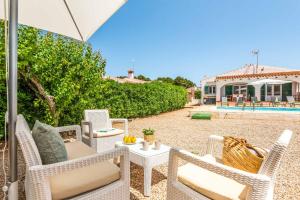 eine Terrasse mit Stühlen und einem Tisch mit einem Sonnenschirm in der Unterkunft Villa Xaloc in Port d'Addaia