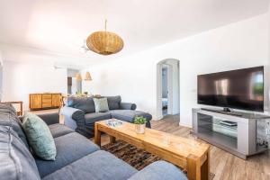 a living room with two couches and a television at Villa Xaloc in Port d'Addaia