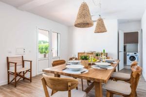 a kitchen and dining room with a wooden table and chairs at Villa Xaloc in Port d'Addaia