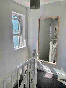a hallway with a mirror and a staircase with a window at 2 Bed Cottage Barnstaple North Devon Dog-Friendly! in Barnstaple