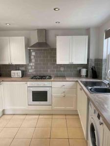 uma cozinha com armários brancos e um forno com placa de fogão em 2 Bed Cottage Barnstaple North Devon Dog-Friendly! em Barnstaple