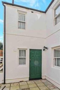 a white house with a green door and two windows at 2 Bed Cottage Barnstaple North Devon Dog-Friendly! in Barnstaple