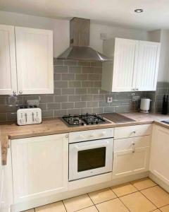 uma cozinha com armários brancos e um forno com placa de fogão em 2 Bed Cottage Barnstaple North Devon Dog-Friendly! em Barnstaple