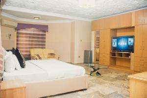um quarto com uma grande cama branca e uma televisão em J's Place em Abuja