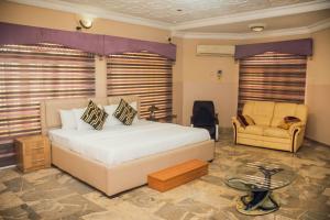 een slaapkamer met een bed, een bank en een stoel bij J's Place in Abuja