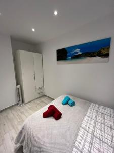 Un dormitorio con una cama con toallas rojas y azules. en Ravel en Alicante