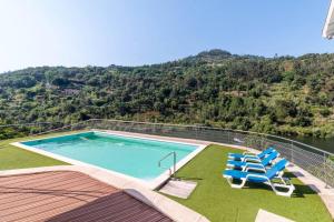 a swimming pool with chairs and a view of a mountain at Casa da Barragem Douro in Cinfães