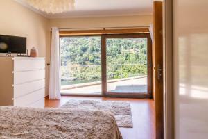 a bedroom with a large window with a view at Casa da Barragem Douro in Cinfães