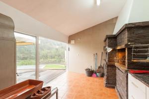 a kitchen with a stone fireplace and a large window at Casa da Barragem Douro in Cinfães