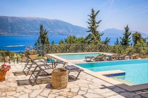 a swimming pool with chairs and a view of the water at Villa Astria in Kefallonia