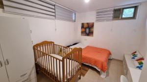 a small bedroom with a bed and a crib at שני חדרי שינה, חניה חינם, איזור שקט ויוקרתי, in Rechovot